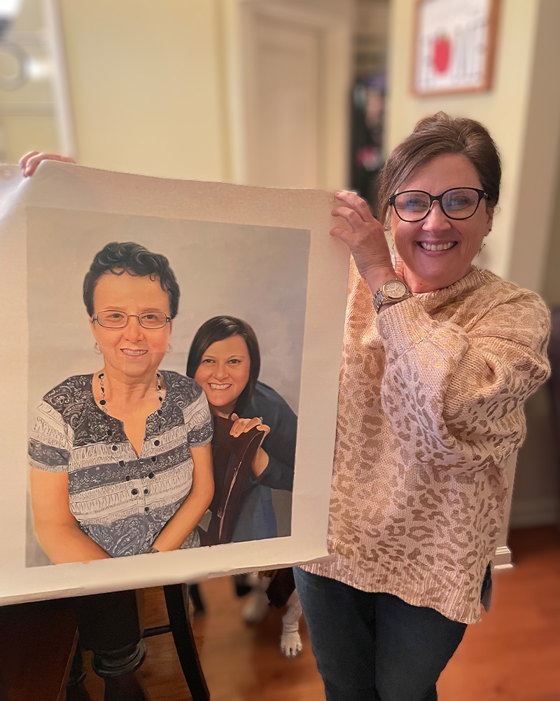 Woman holding unframed custom portrait of two women